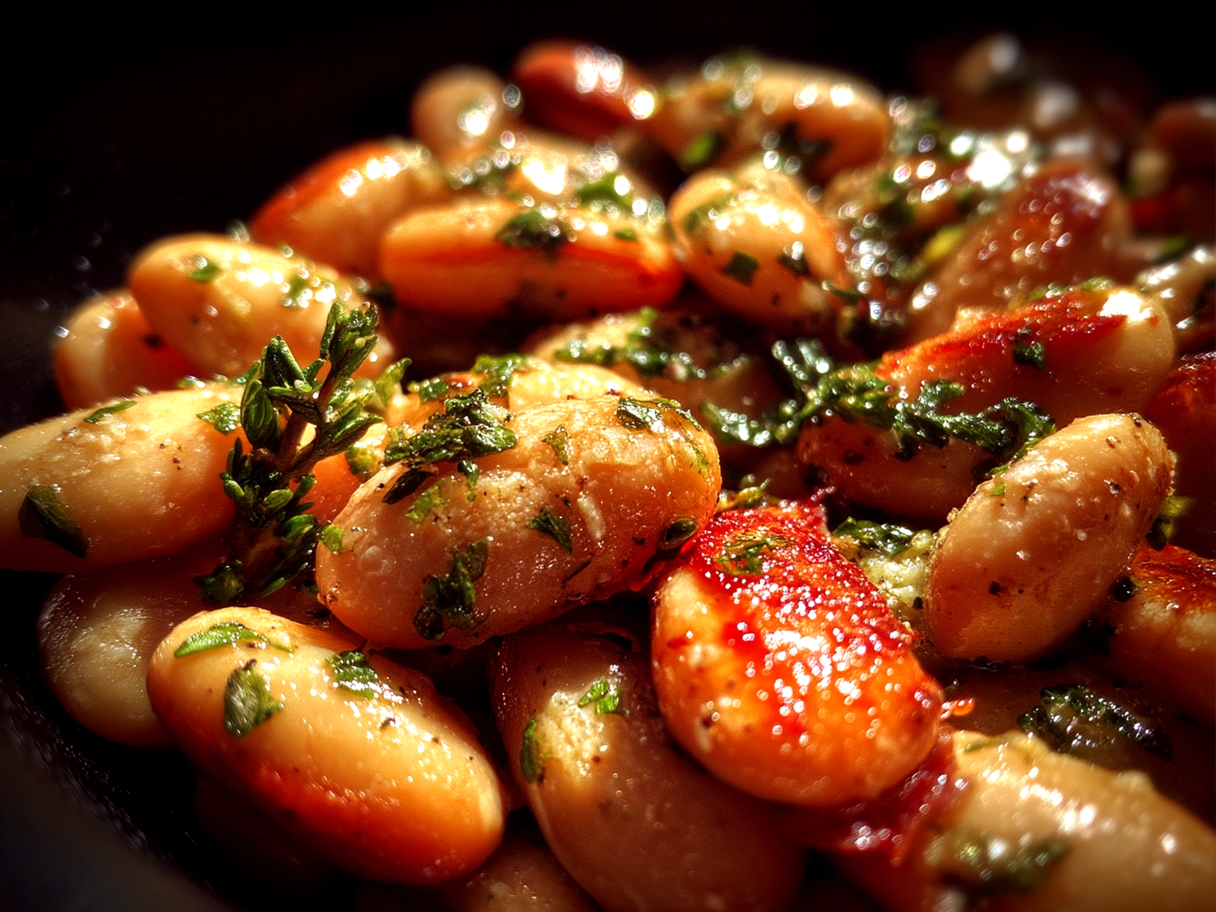 Slight angle close up of finished creamy miso butter beans garnished with fresh herbs